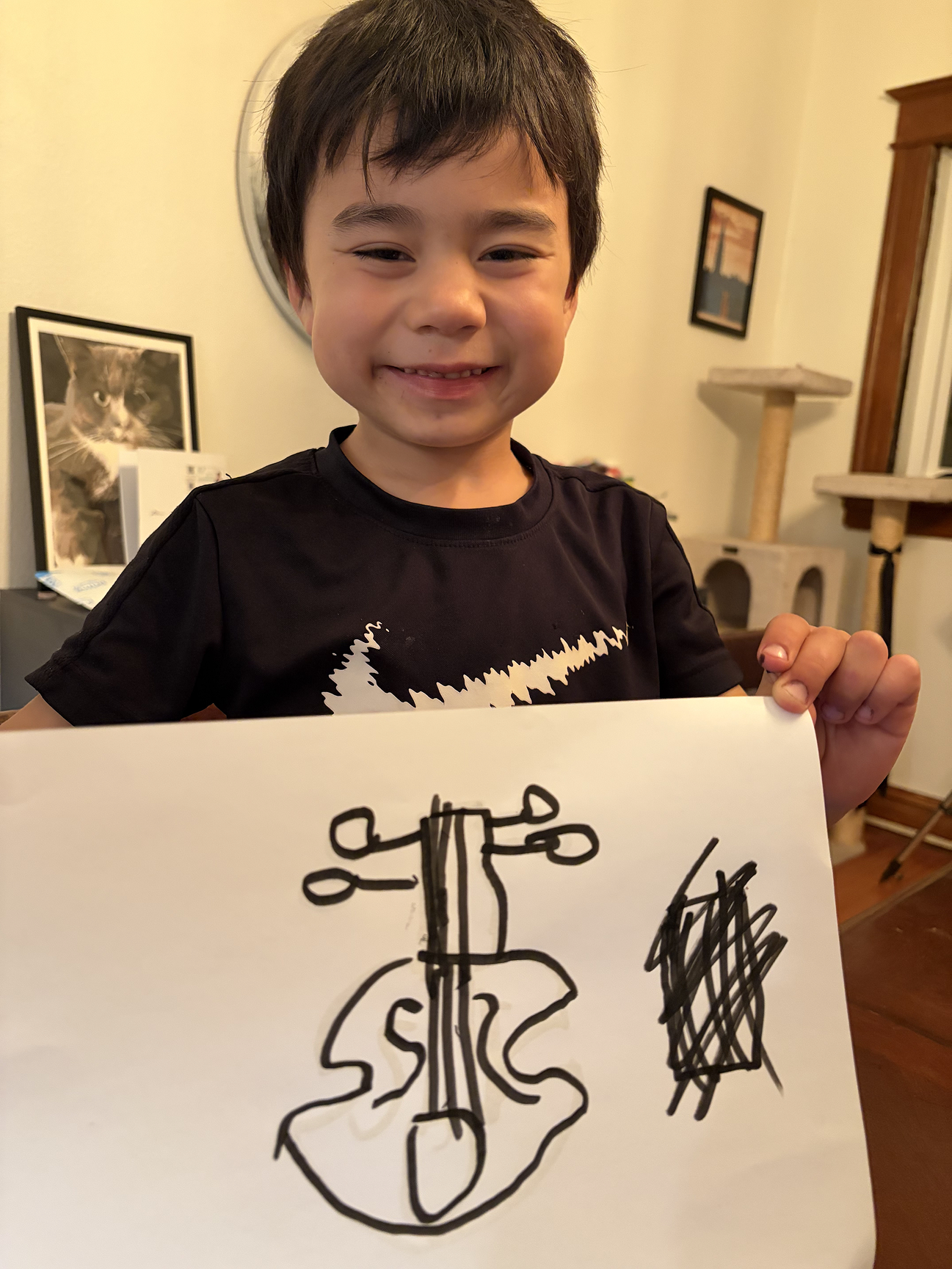 A young violin student proudly holding up a hand-drawn picture of a violin